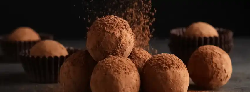 Chocolate truffles with powdered chocolate falling on top of them